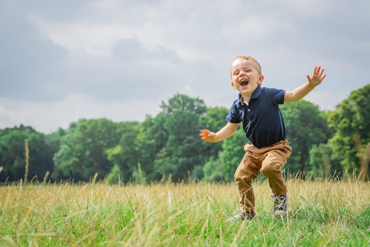 A boy, looking happy, plays in the meadow during a photoshoot at the Ashridge Estate