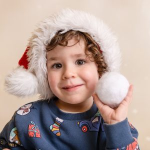 Photo of a boy wearing a santa hat throwing a snowball