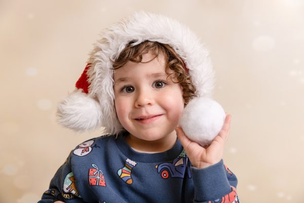 Photo of a boy wearing a santa hat throwing a snowball