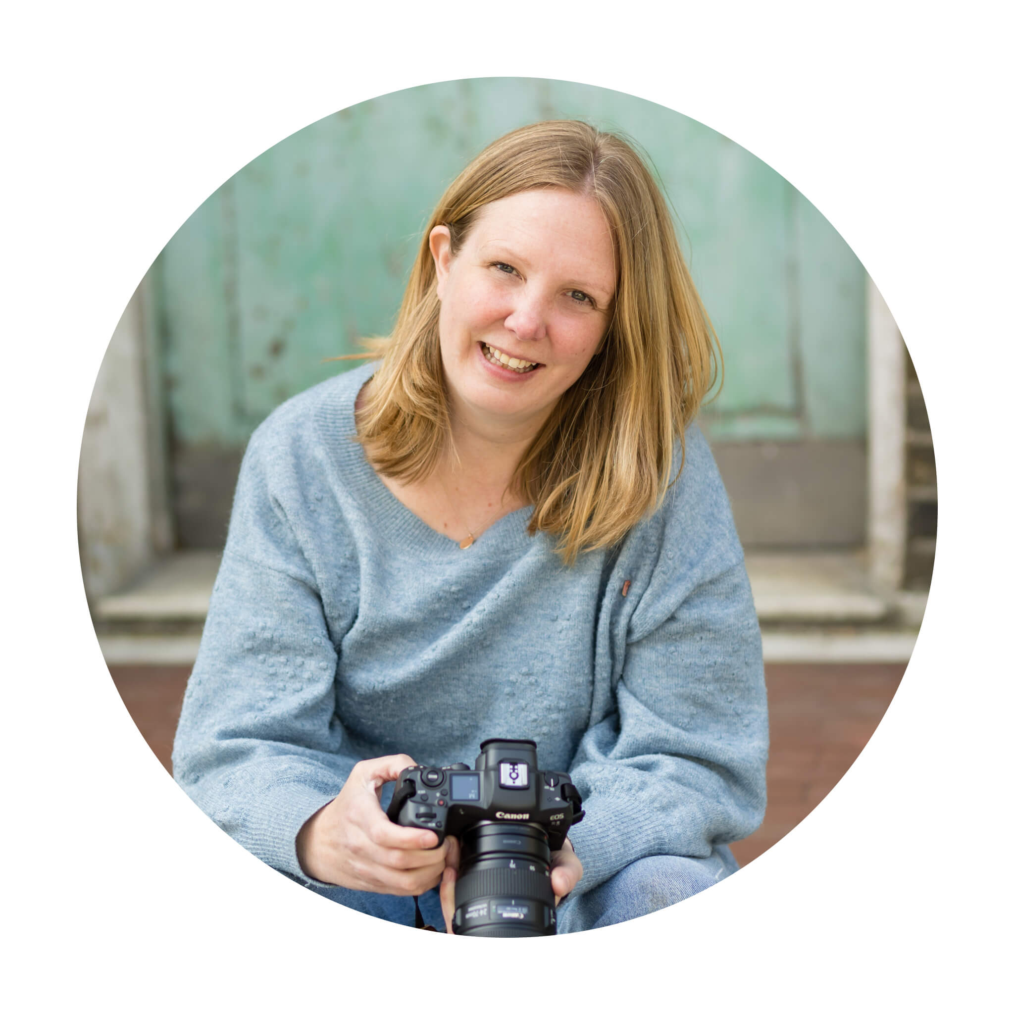 Lyndsey Abercromby, a Berkhamsted Photographer, sits holding her camera and smiling at the camera
