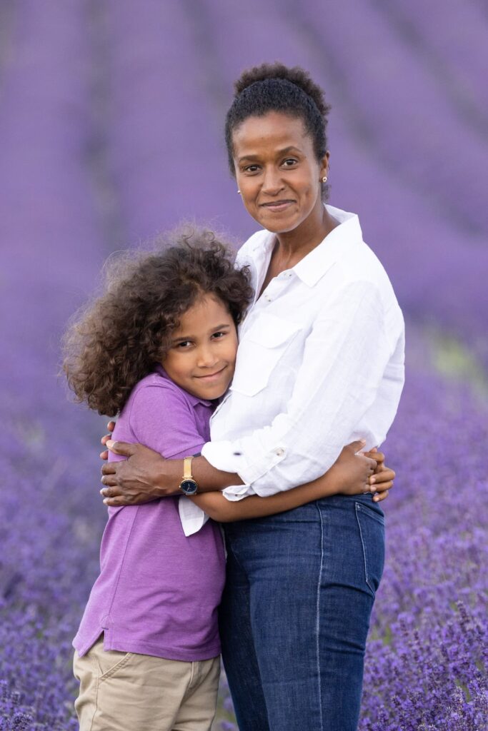 Mother and son hug in the purple lavender fields at Hitchin, both smiling warmly at camera