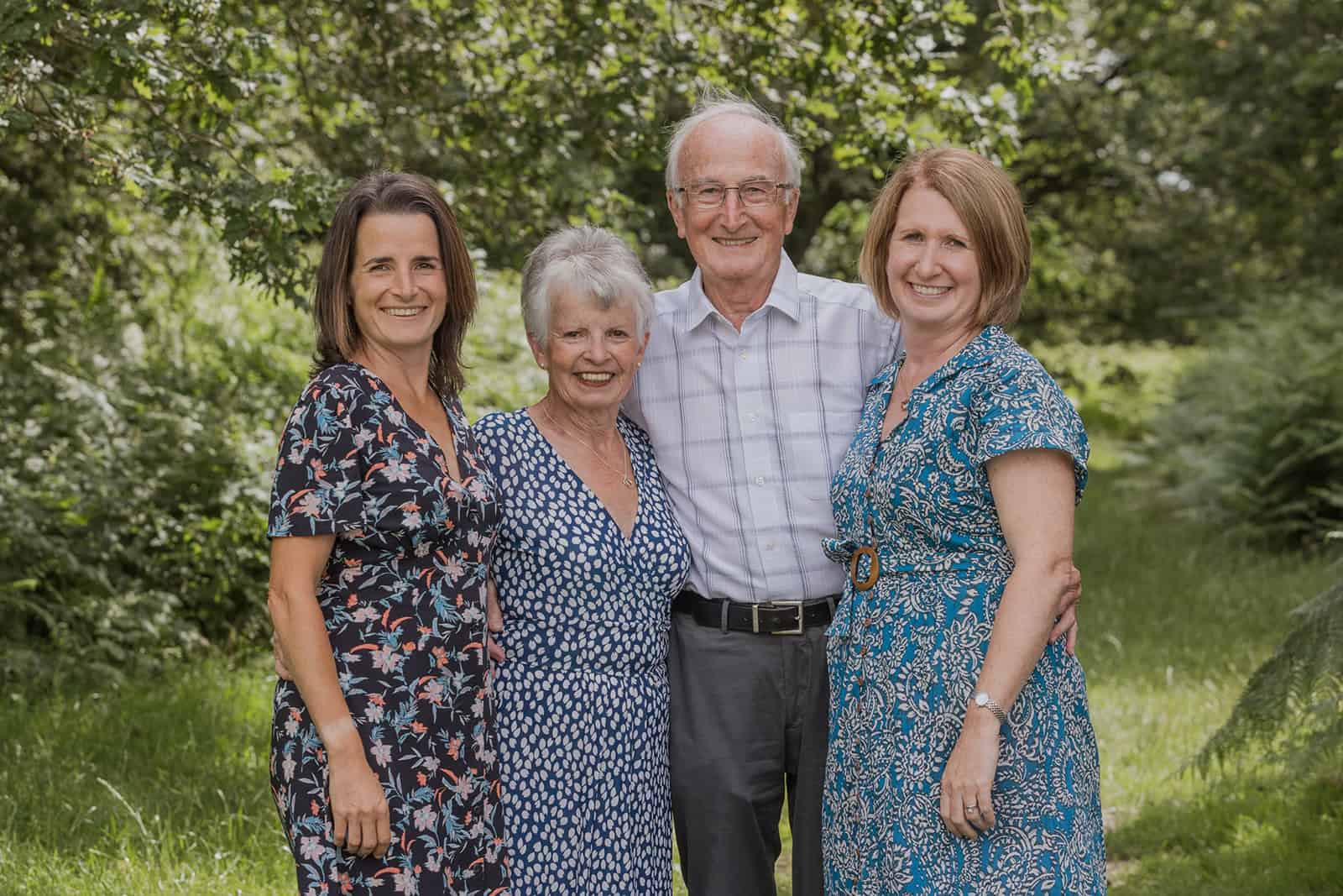 Grandparents and their adult children stand together in a beautiful outdoor area