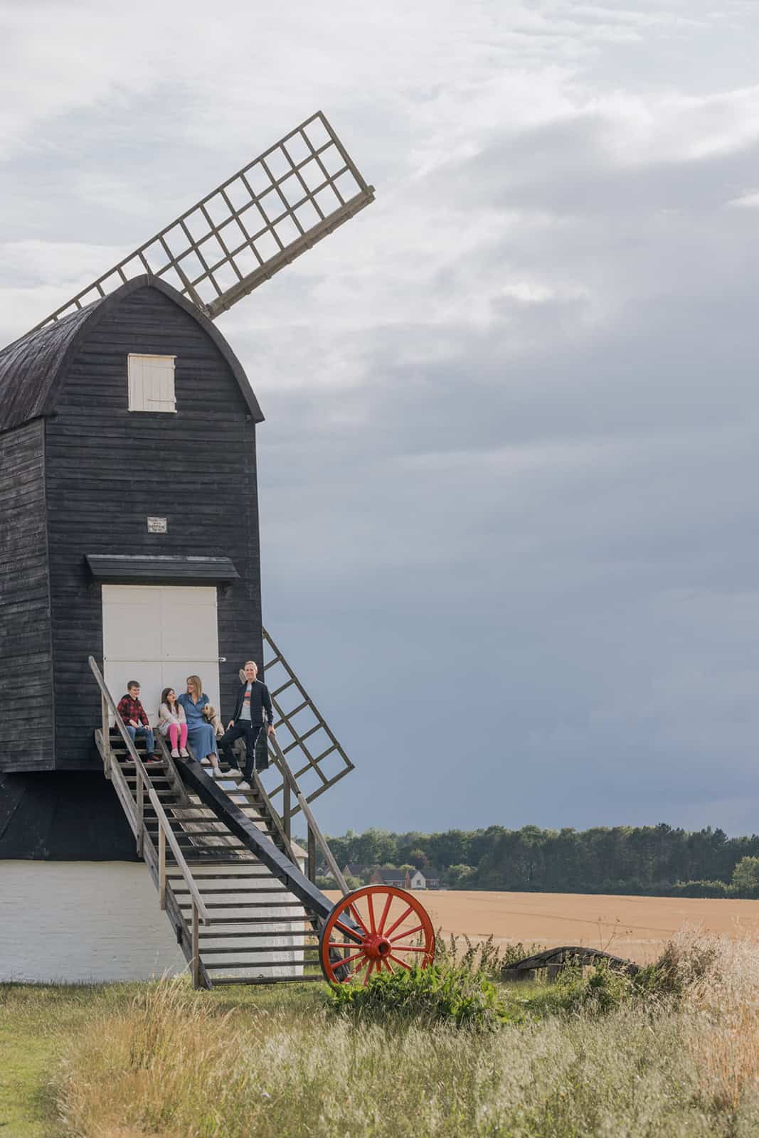 A family relax on the steps of Pitstone Windmill during a family photoshoot