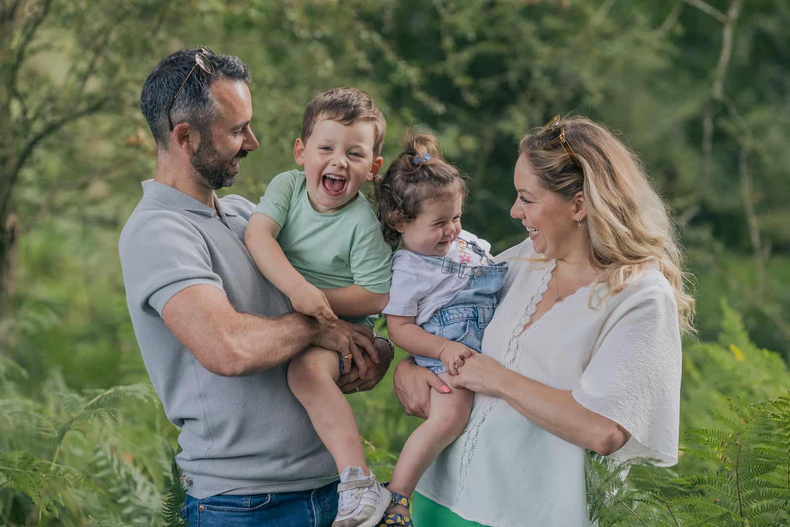 A photograph capturing natural giggles as parents tickle their children during a relaxed family photoshoot