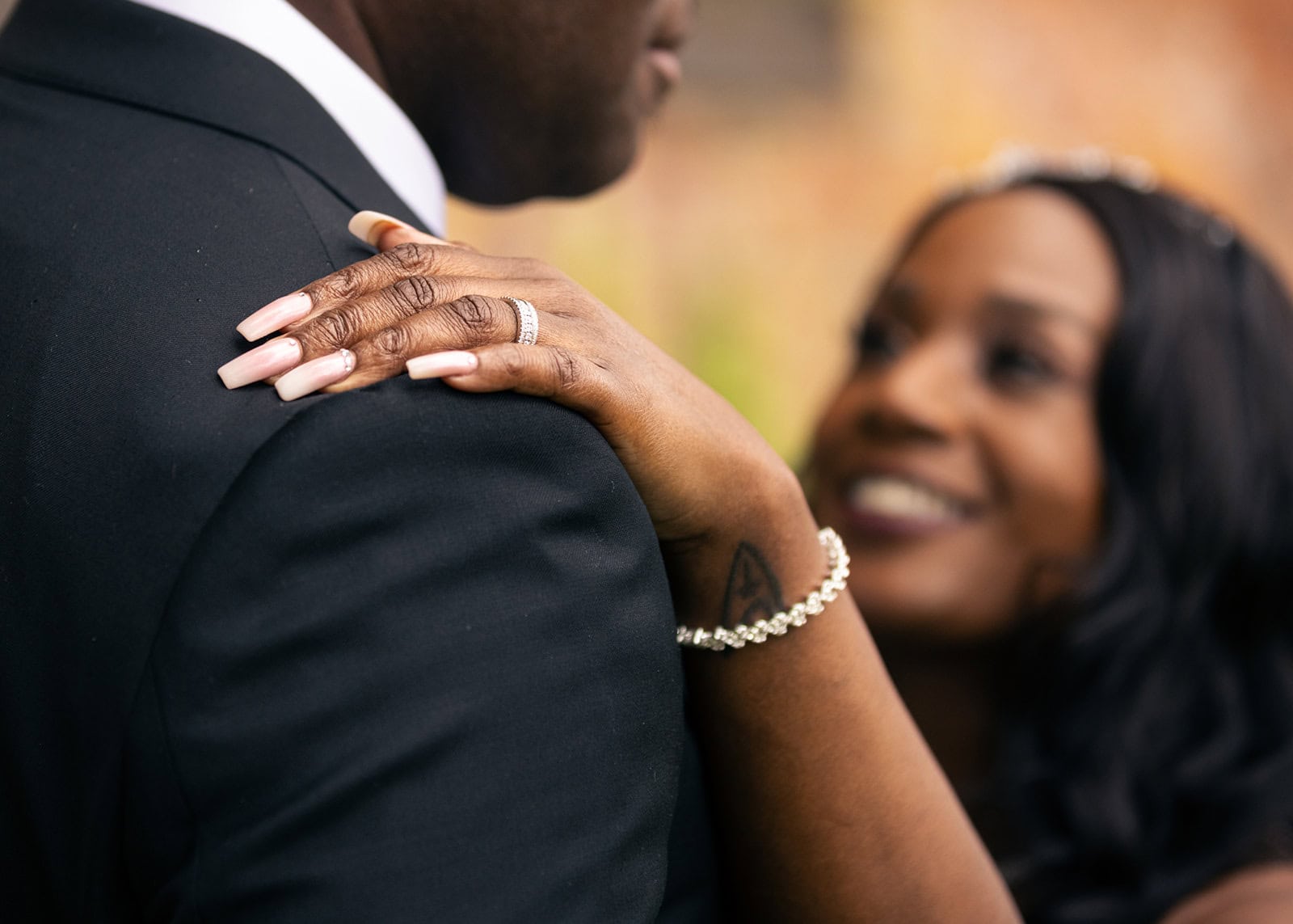 A bride shows off her new wedding ring, resting it on her partners shoulder