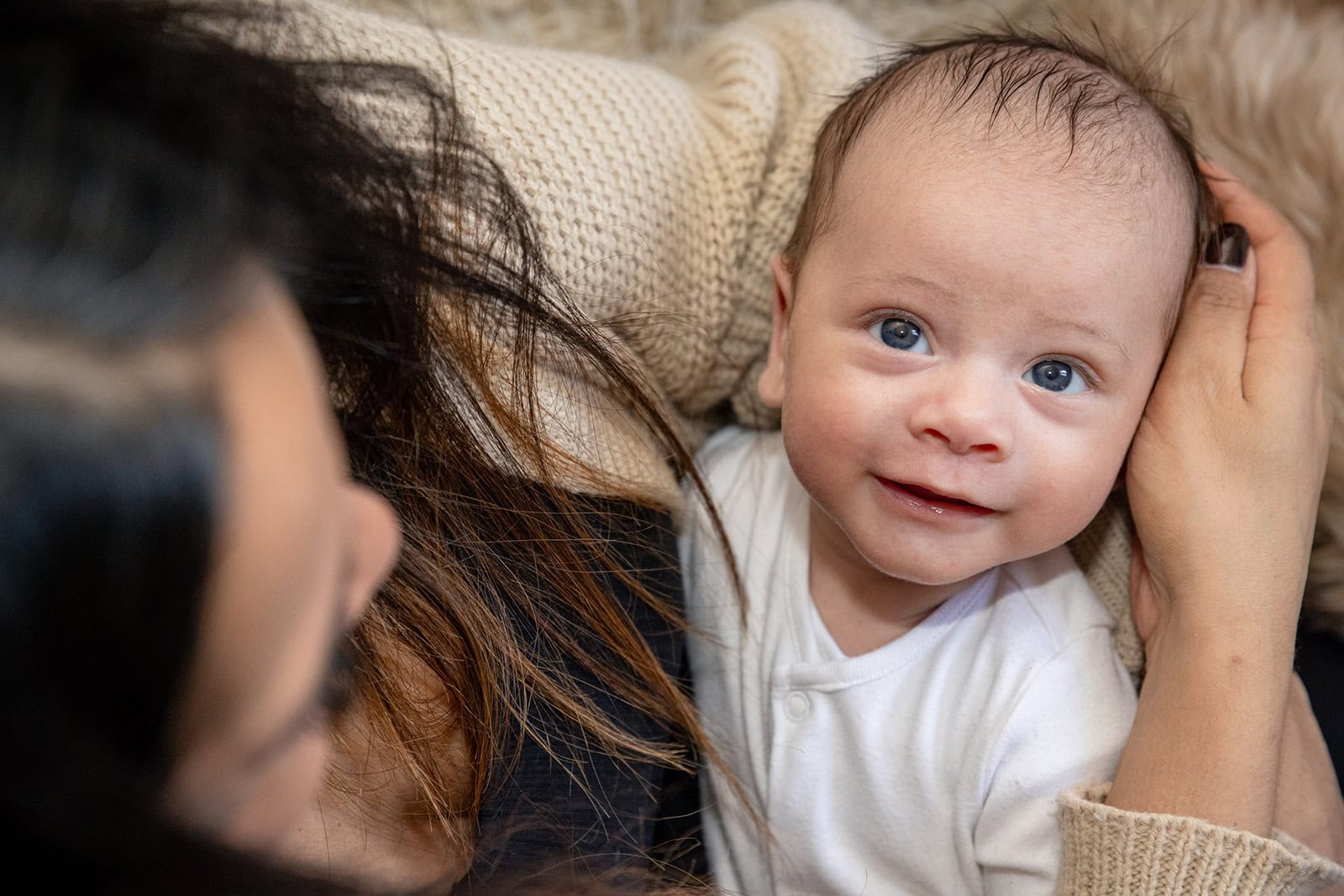 A newborn looks up at the camera while he resits in his mums arms in Leighton Buzzard