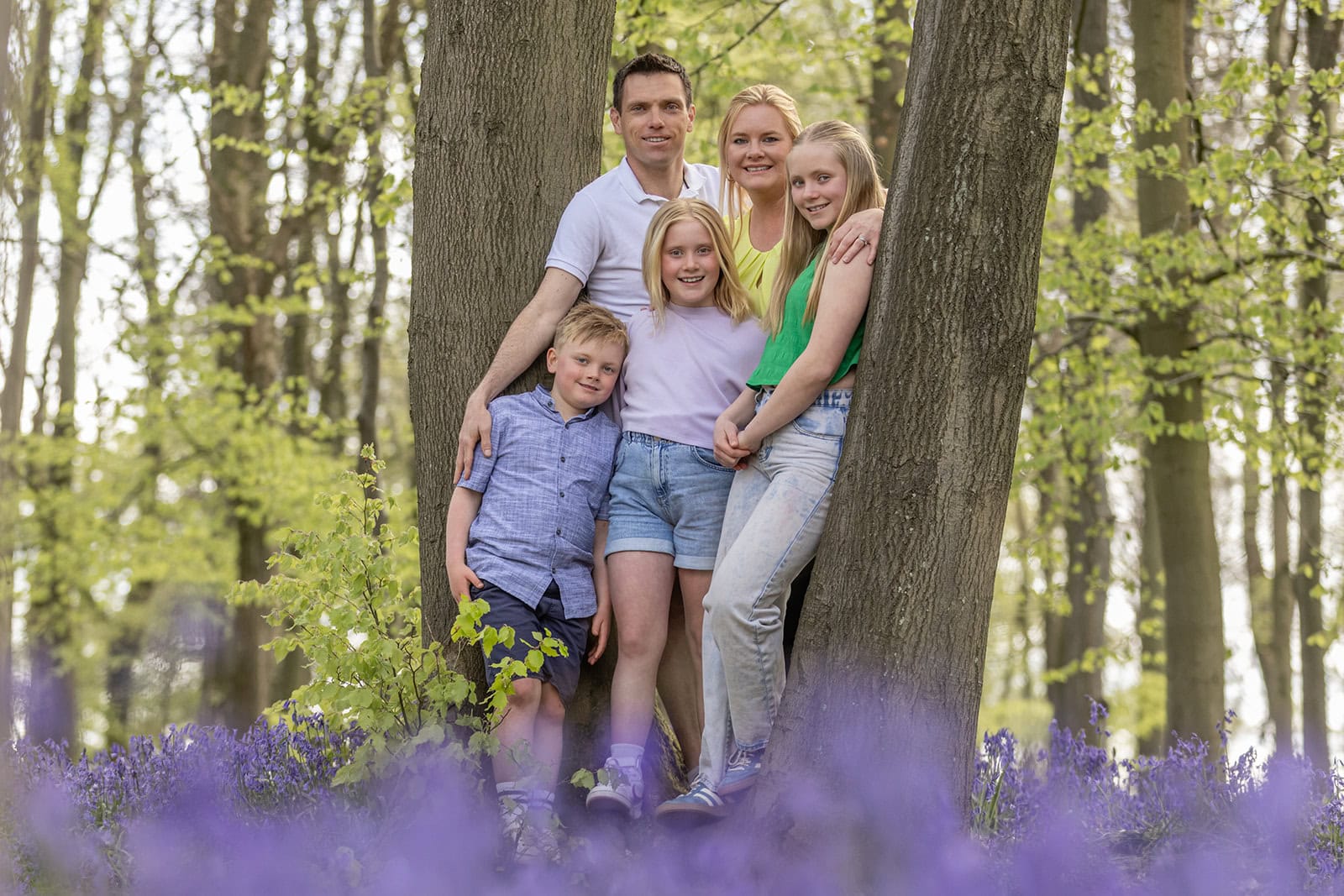 A family stand together ,surrounded by a carpet of bluebells
