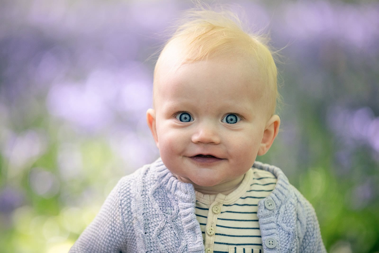 A baby smiles for a photo in the bluebells at Ashridge near Tring