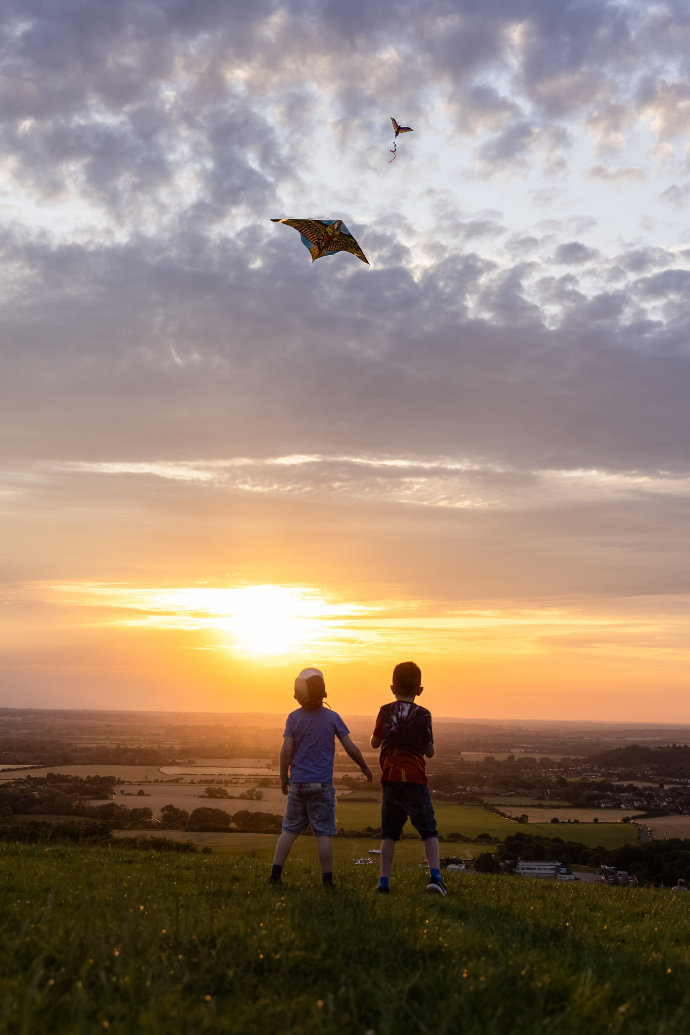 A silhouette of two boys flying a kite at Dunstable Downs, near Tring, at sunset