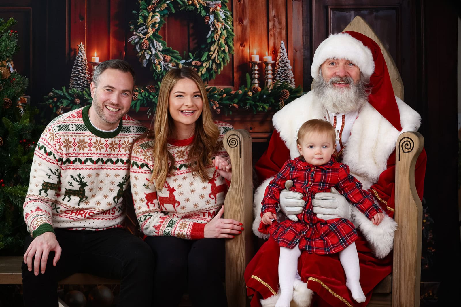 A family sit with Santa smiling at the camera during a Santa photoshoot Experience in Berkhamsted.