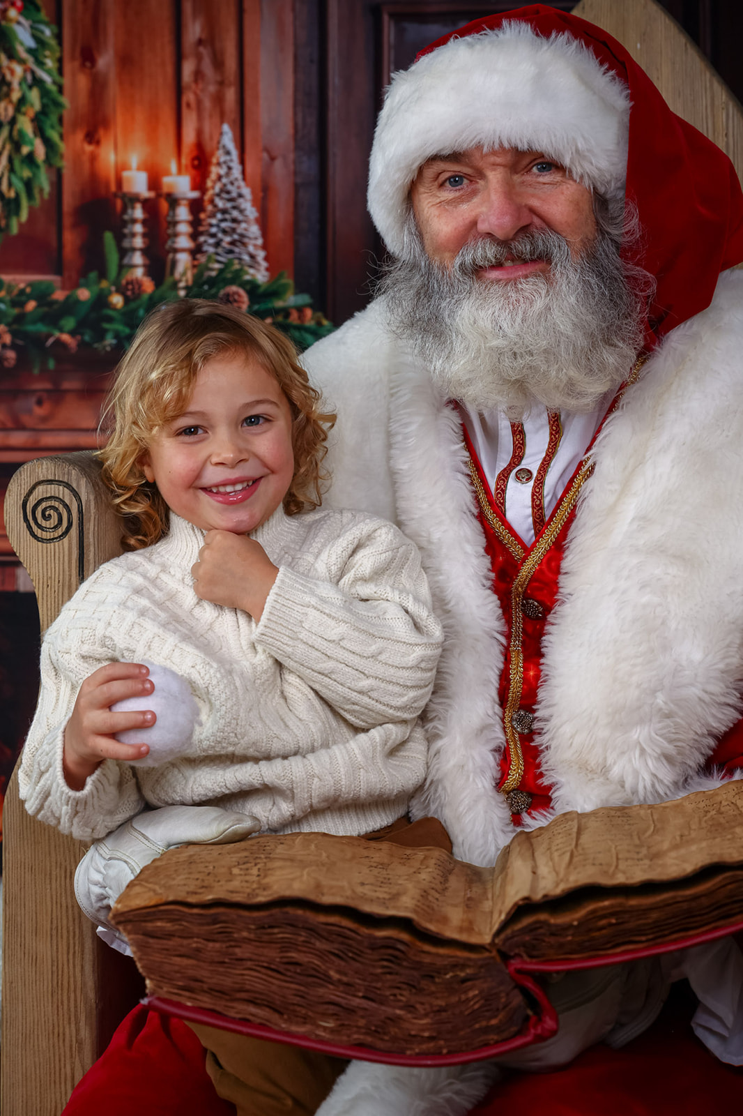Boy checks whether his name is on the nice list with Santa, during a Santa visit and photoshoot near St Albans