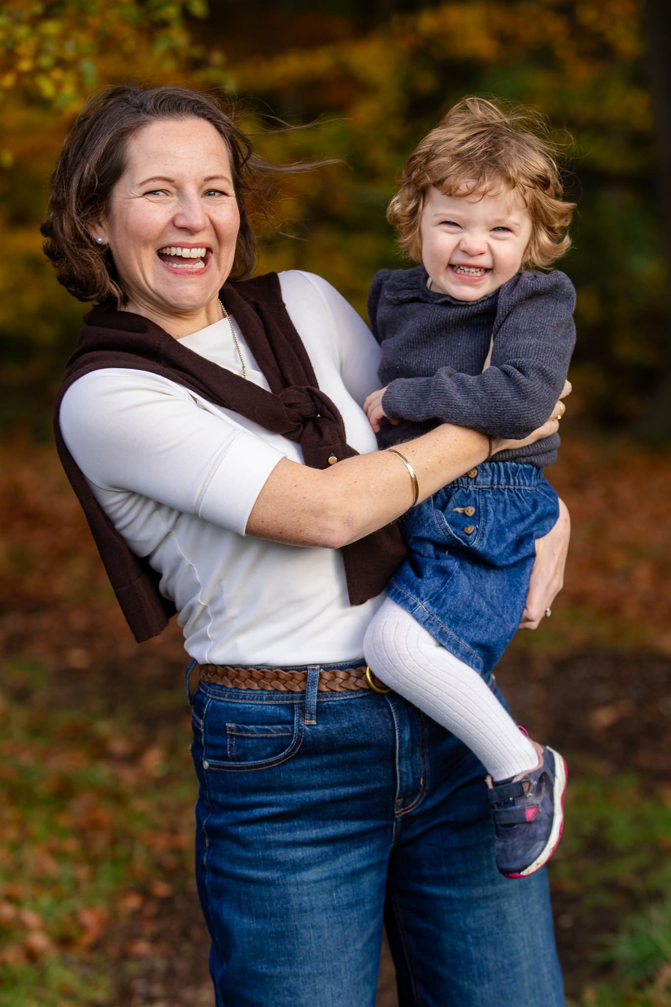 A girl and her mum smile while playing and spinning at the Ashridge Estate in autumn
