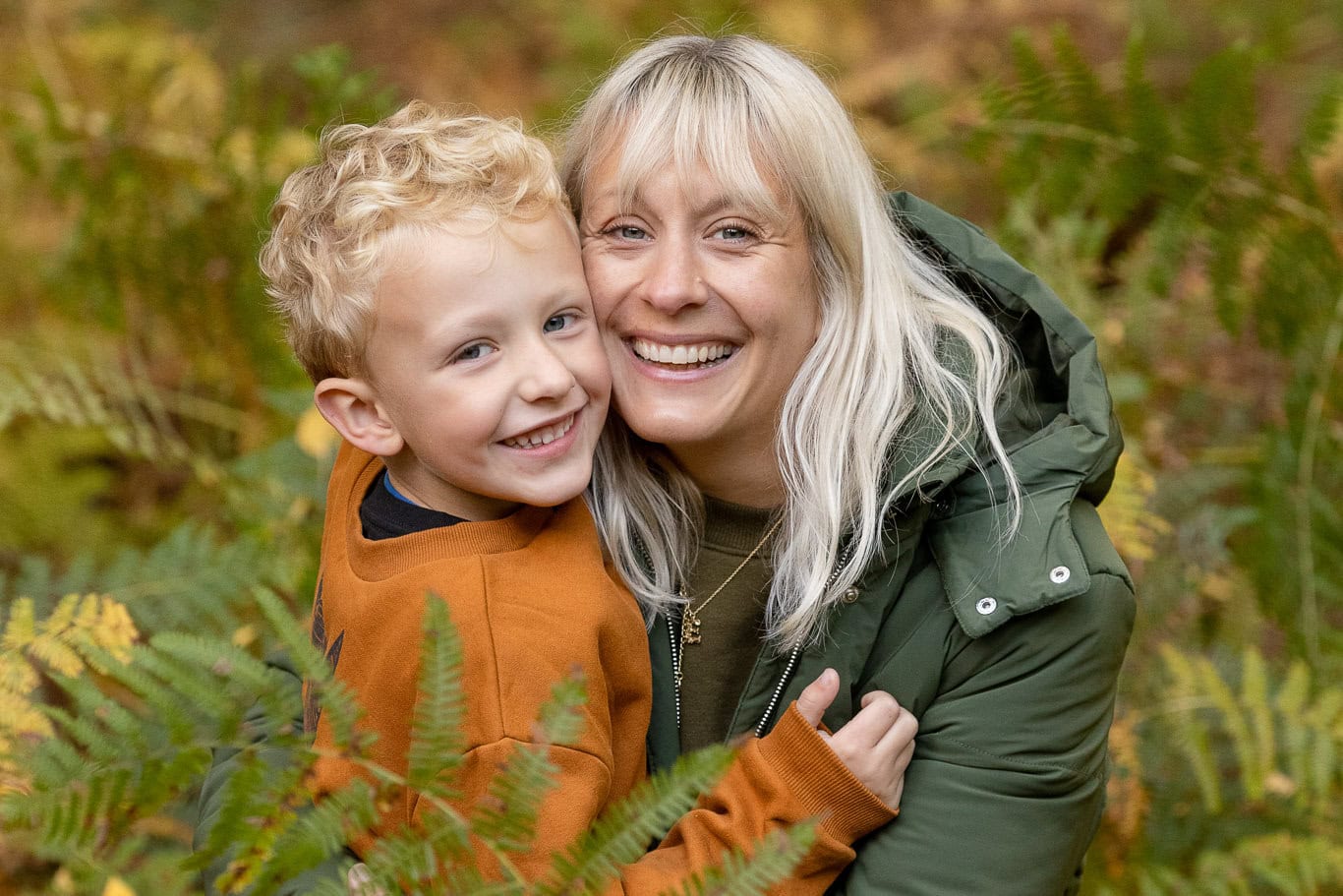 A family smile at the camera nestled between the leaves on Northchurch Common