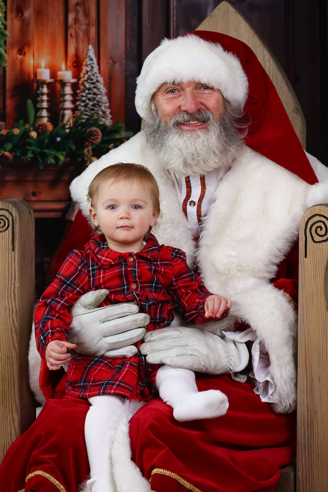 A girl and Santa smile at the camera during a santa photoshoot