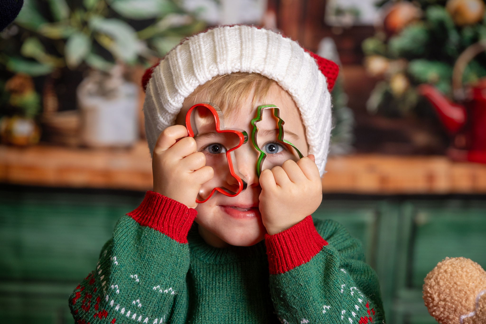 A boy uses two cookie cutters as glasses during a family Christmas photoshoot activity near Kings Langley